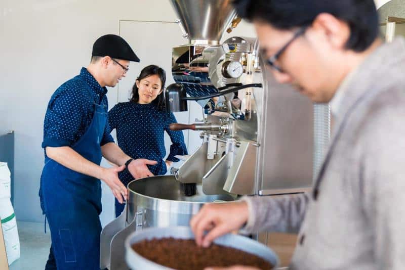 Coffee roaster teaching an apprentice how to roast coffee beans