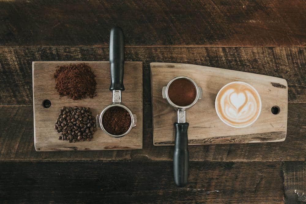 Coffee beans beside coffee powder on brown wooden board